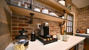A kitchen with a coffee machine, jars, and shelves with dishes. - Backstage Gallery House (Decatur)