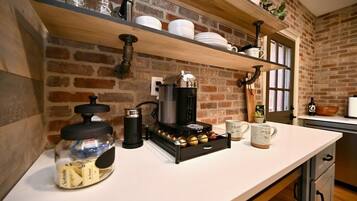 A kitchen with a coffee machine, jars, and shelves with dishes.