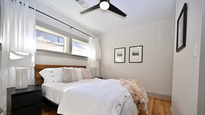 A bedroom with a bed, bedside tables, a ceiling fan, and two framed pictures on the wall. - Backstage Gallery House (Decatur)