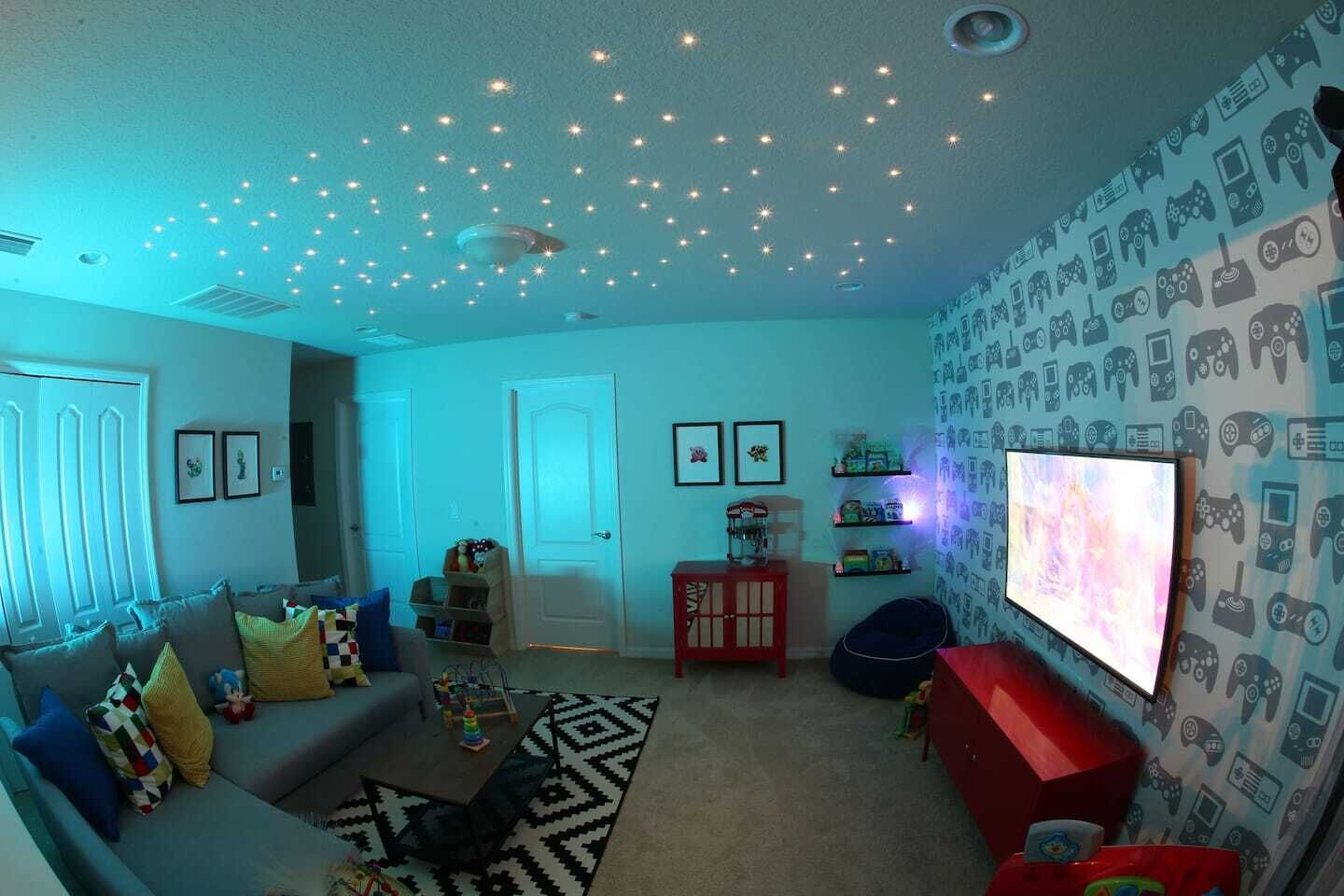 A living room with a sofa, a coffee table, a TV, and a patterned wall.