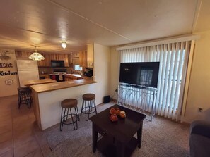 A compact living space with a kitchen area, a dining table, and a TV.