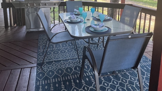 A covered outdoor dining area with a grill, tables, and chairs. - Cozy cabin in a peaceful place (Ruidoso)