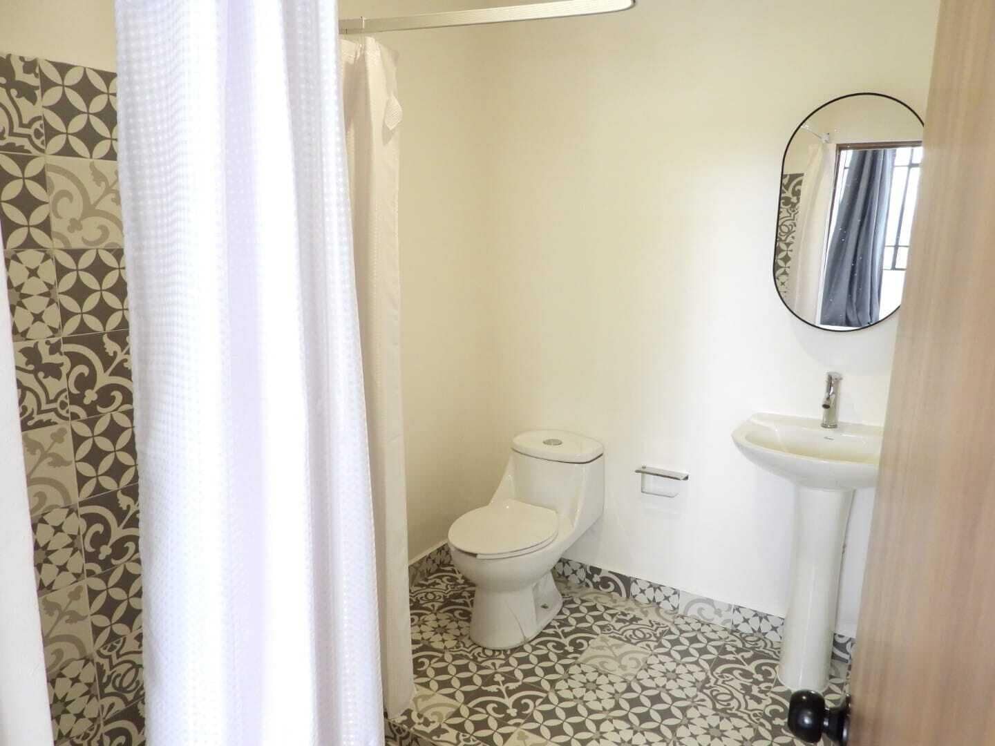 A bathroom with a toilet, sink, and patterned floor tiles.