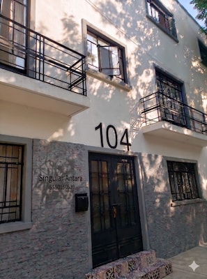 A building with the number 104, a black door, and a window with a metal grill. - Singular Antara Polanco (Mexico City)