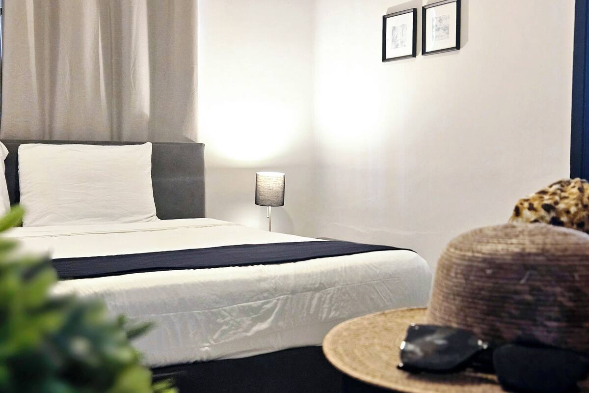 Une chambre à coucher moderne avec un lit, une lampe de chevet et un cadre photo fixé au mur.