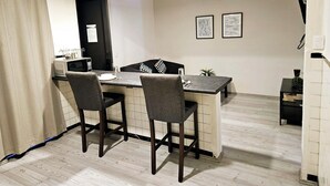 Ein kleiner Essbereich mit Küchenzeile, zwei Stühlen, einem Tisch und einer Mikrowelle.