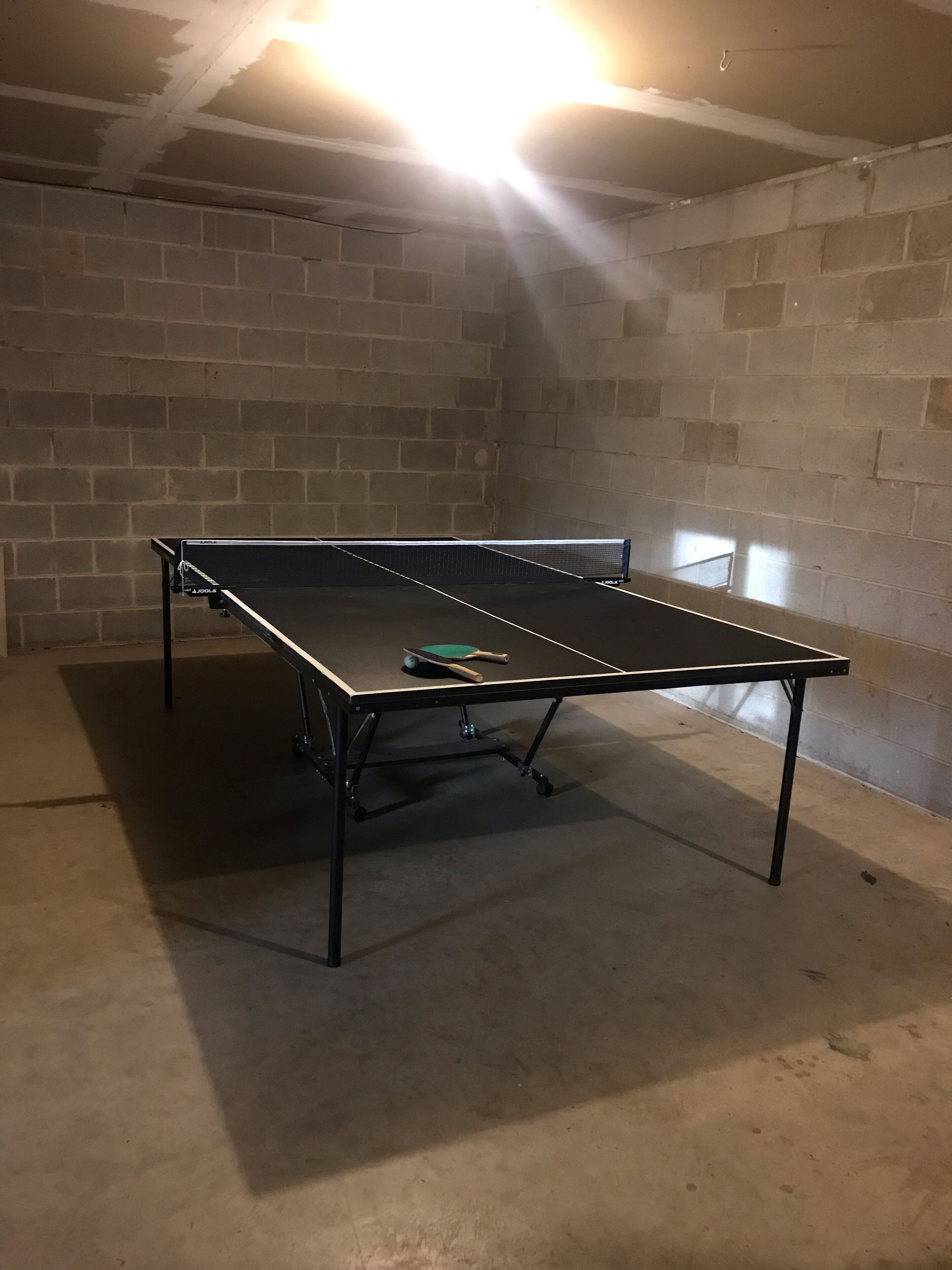 Un tavolo da ping pong in una stanza con pareti in mattoni e pavimento in cemento.