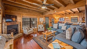 A cozy log cabin interior with a fireplace, comfortable seating, and a kitchen area. - Eagle’s Crest at Mentone-Amazing Views, sleeps 8 (Mentone)