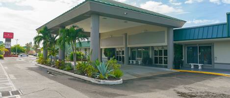 A gas station with a covered canopy, palm trees, and a sign for Ramada.