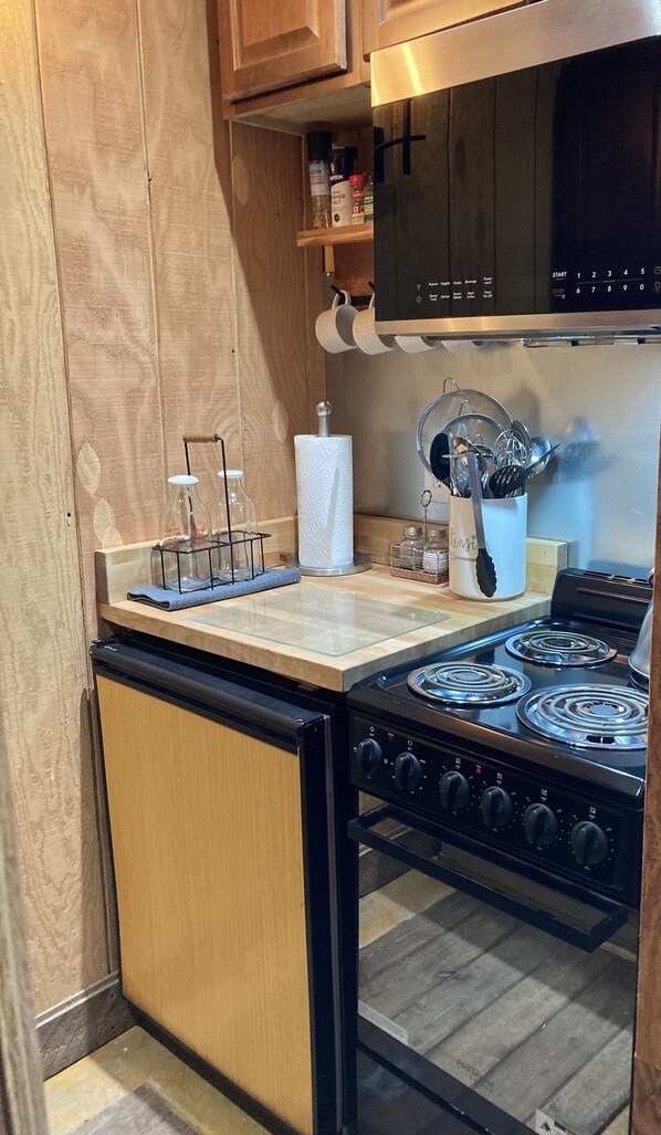 A compact kitchen with a stove, oven, and wooden cabinets.