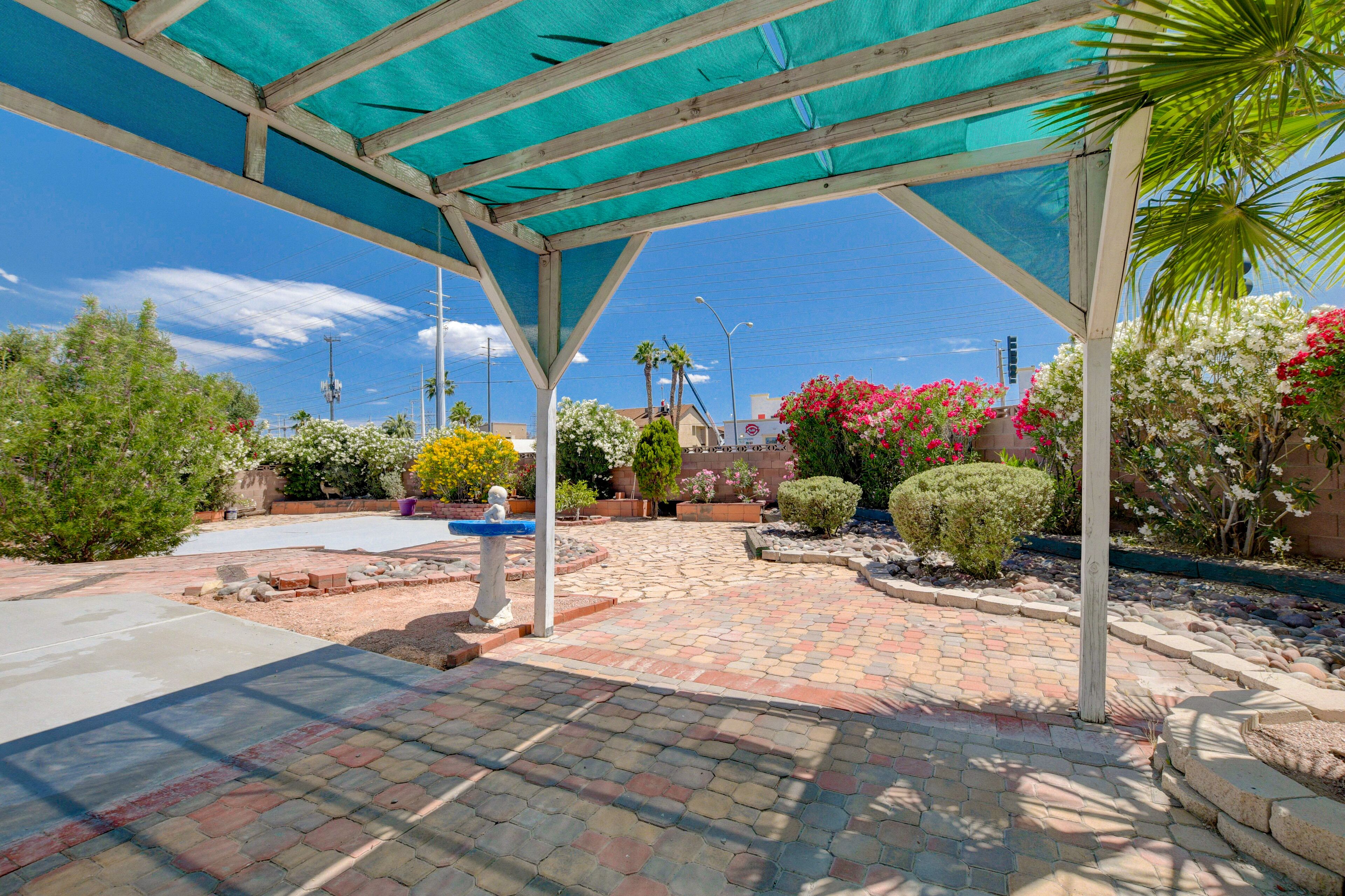 Un patio al aire libre con una pérgola, plantas en macetas y un camino de ladrillo.