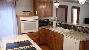 A kitchen with wooden cabinets, a white dishwasher, a stove, a microwave, and a sink.