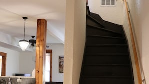 A staircase with a wooden handrail and black steps, leading to an upper floor.