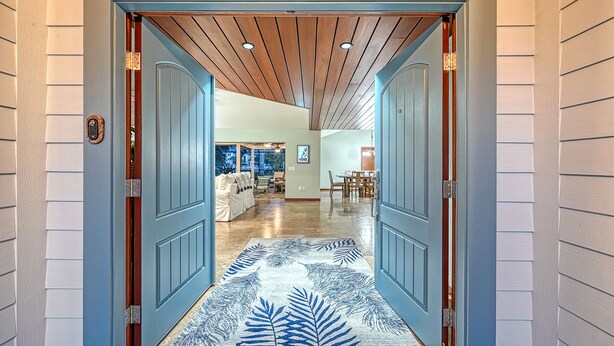 Un pasillo con una puerta azul que da a una sala de estar con una mesa y sillas de comedor.
