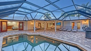 Un espacio al aire libre techado con piscina, asientos y zona de comedor.
