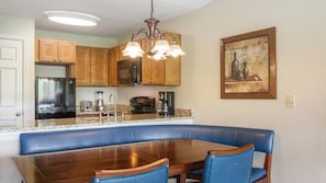 Eine Küche mit Holzschränken, einer eingebauten Kochinsel, einem Esstisch mit Stühlen und einer Pendelleuchte.