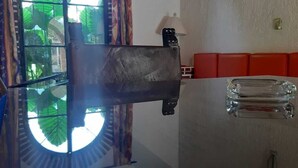 Une pièce dotée d’une grande fenêtre, d’un banc rembourré de couleur rouge et d’un luminaire fixé au mur.