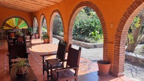 Une terrasse couverte agrémentée d’arcs en briques, de carreaux de terre cuite et de plantes en pot.
