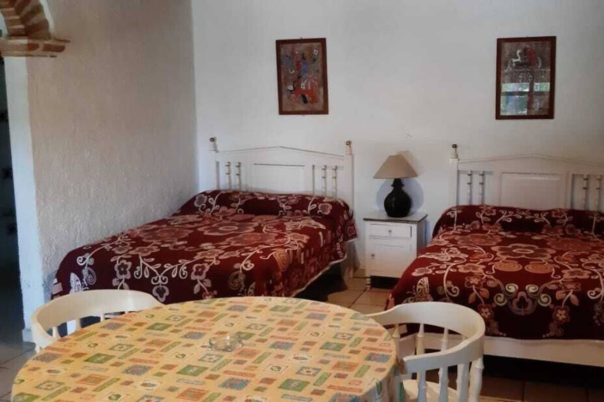 A room with two single beds, a small table, and a chair. There are two bedside tables with lamps.