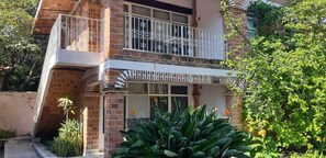 A two-story building with a balcony, brick facade, and surrounding greenery. - Capital O Posada Del Pescador Jocotepec (Jocotepec)