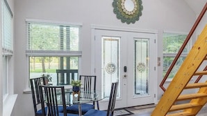 A dining area with a glass table and chairs, a decorative mirror on the wall, and a wooden ladder. - Country guesthouse w/ shared pool, firepit, and outdoor kitchen access (Lexington)