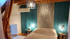 Ein Schlafzimmer mit einem großen Bett, zwei Nachttischen mit Lampen, einer Holzzahlende und teal-farbenen Wänden.