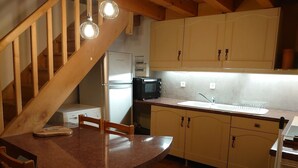 Eine Küche mit Holzausstattung, einem Kühlschrank, einer Mikrowelle und einem Spülbecken.
