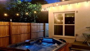 Un giardino sul retro con idromassaggio, recinzione in legno e luci decorative.
