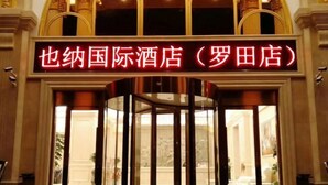 Entrada de hotel con puerta giratoria y un cartel en caracteres chinos.