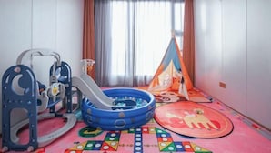Zona de juegos infantiles con tobogán, piscina inflable y una carpa.