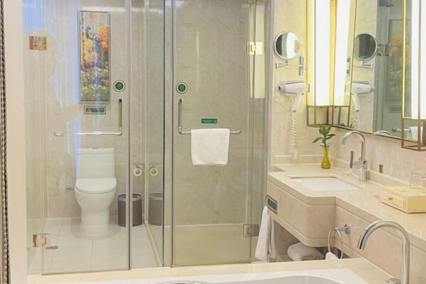 Un baño moderno con ducha de vidrio, inodoro y tocador con lavamanos y espejo.
