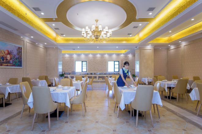 A hotel dining area with round tables, chairs, and a central service area.