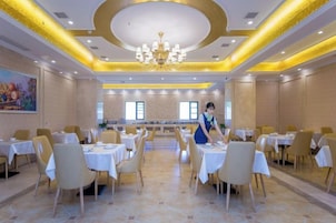 Un comedor de hotel con mesas redondas, sillas y una zona de servicio central.