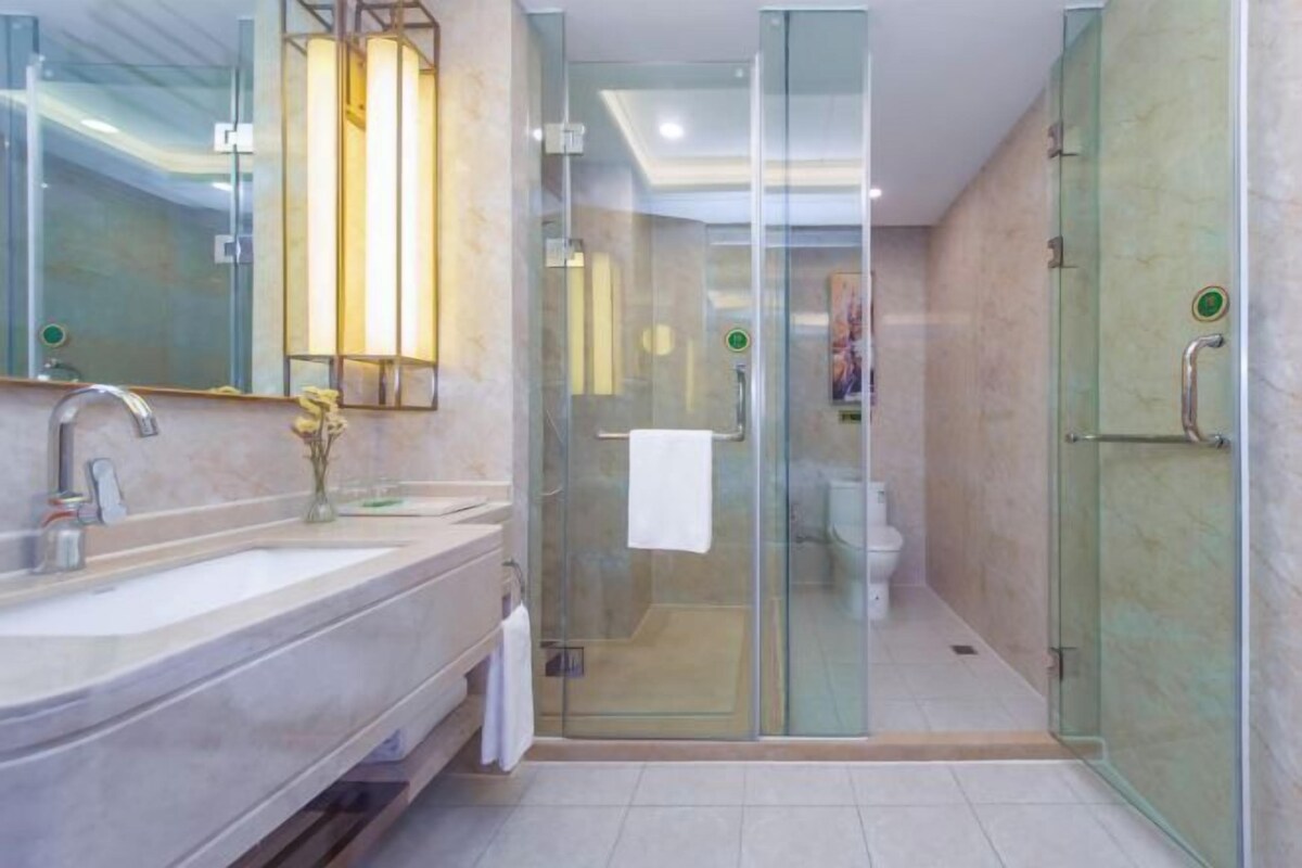 Un baño moderno con ducha envuelta en vidrio, un espejo grande y un lavabo de mármol.