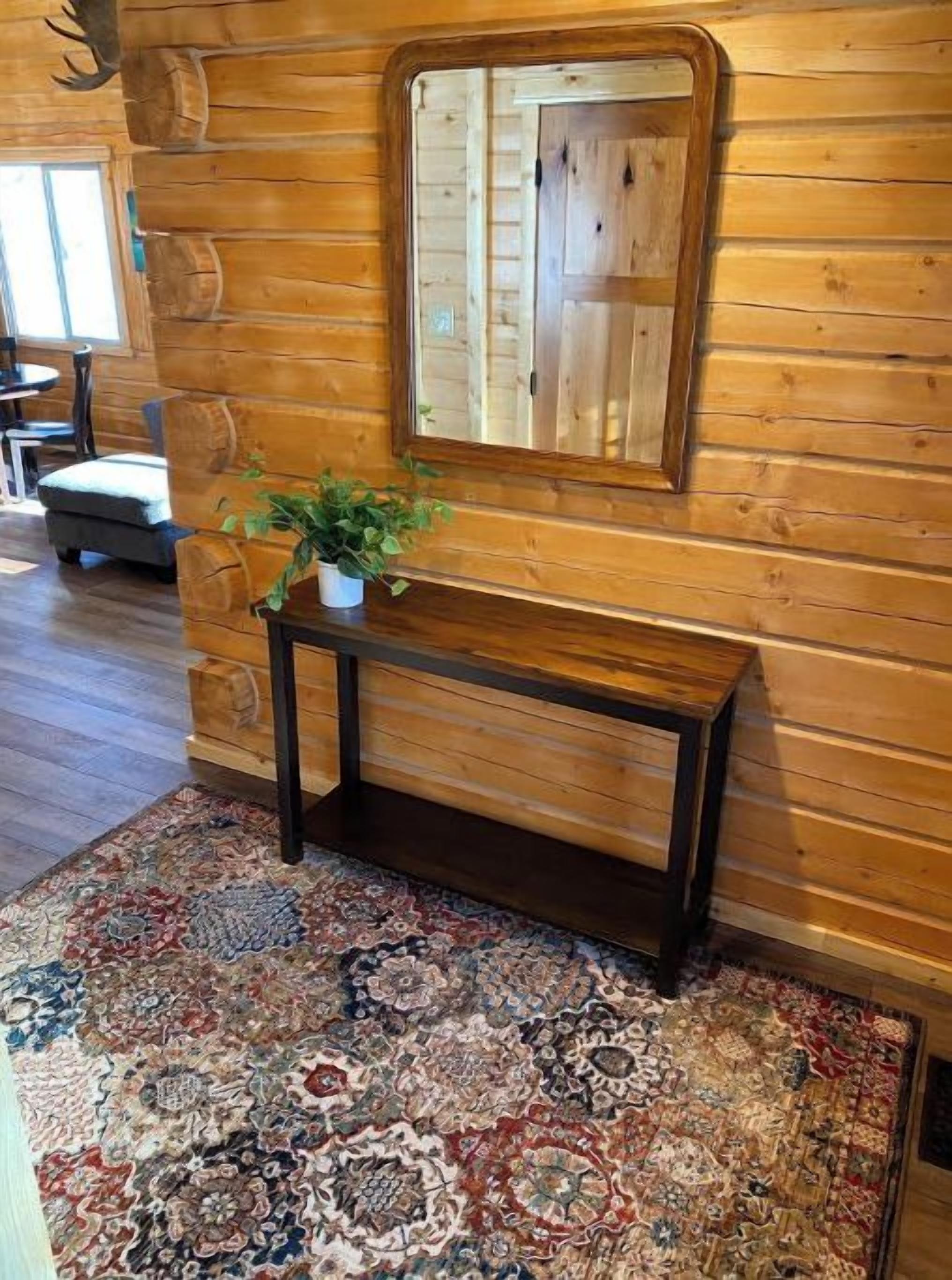 A wooden interior with a patterned rug, a bench, and a mirror on the wall.