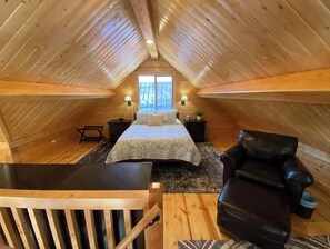A cozy attic bedroom with a bed, two nightstands, a chair, and a desk. - Beautiful Comfy Alaskan Log Home 2 (Wasilla)