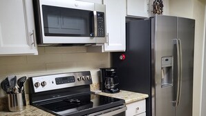 Una cocina moderna con electrodomésticos de acero inoxidable, armarios blancos y encimera de granito.