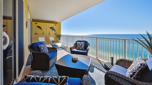 Ein Balkon mit Korbmöbeln, einem Glastisch und Blick auf das Meer.
