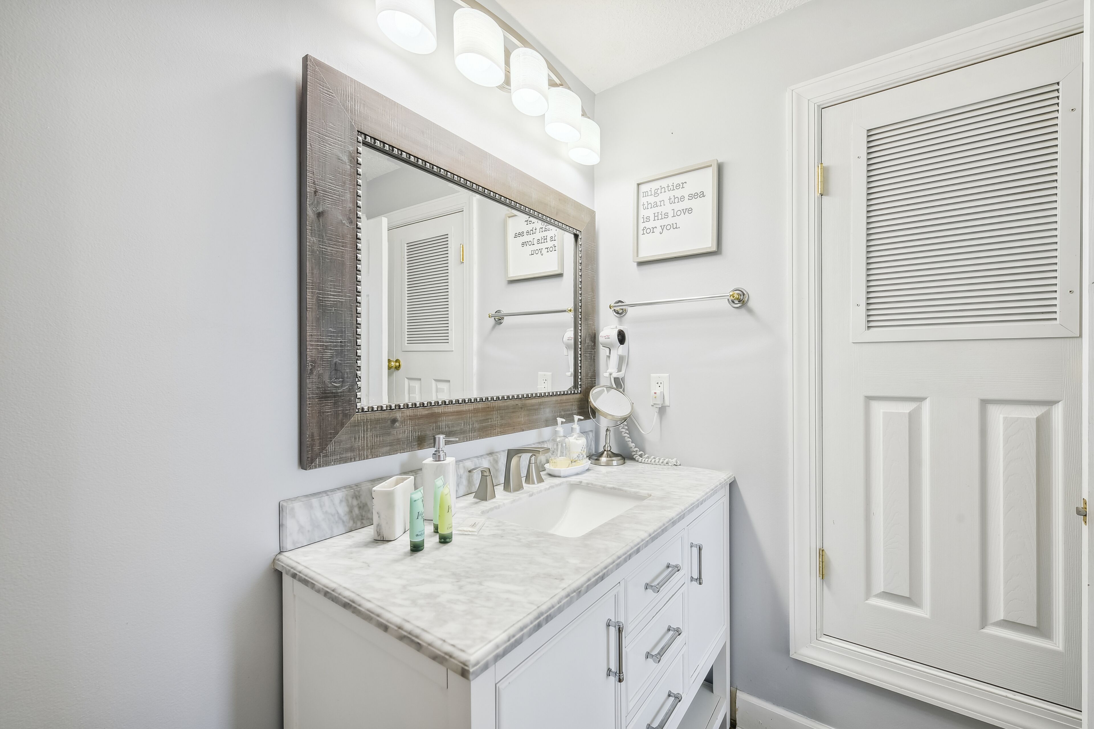 Un bagno con uno specchio grande, un lavandino e una porta con una finestra.