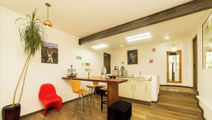 Une cuisine moderne avec un plancher en bois, une chaise rouge, un pouf noir et une plante en pot.