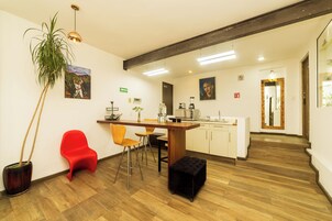 Une cuisine moderne avec un plancher en bois, une chaise rouge, un pouf noir et une plante en pot.