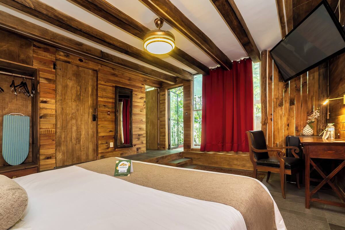 A wooden room with a bed, a desk, and a TV.