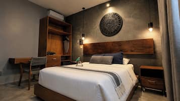 Un dormitorio moderno con una cama grande, un escritorio de madera y un aire acondicionado instalado en la pared.