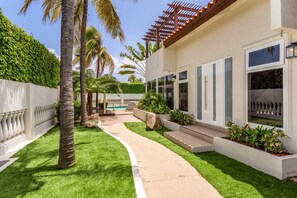 Ein modernes Haus mit Pool, umgeben von gepflegten Rasenflächen und Palmen.