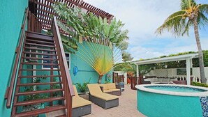 Un área de piscina con escaleras, sillas de descanso y un espacio de estar cubierto.