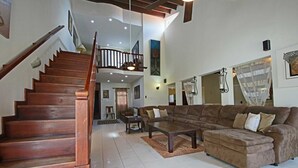Un amplio espacio de estar con una escalera de madera, un sofá marrón grande y una mesa de comedor.