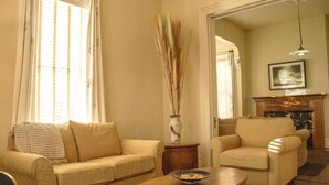Ein Wohnzimmer mit einem beigen Sofa, einem Holztisch und einer Vase mit hohen Gräsern.