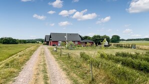 Propiedad rural con camino de grava que lleva a un granero rojo y una construcción blanca.