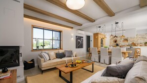 A modern living room with a sofa, coffee table, and a TV. There is a dining area with chairs and a kitchen visible in the background. - Awesome home in Tinjan (Tinjan)