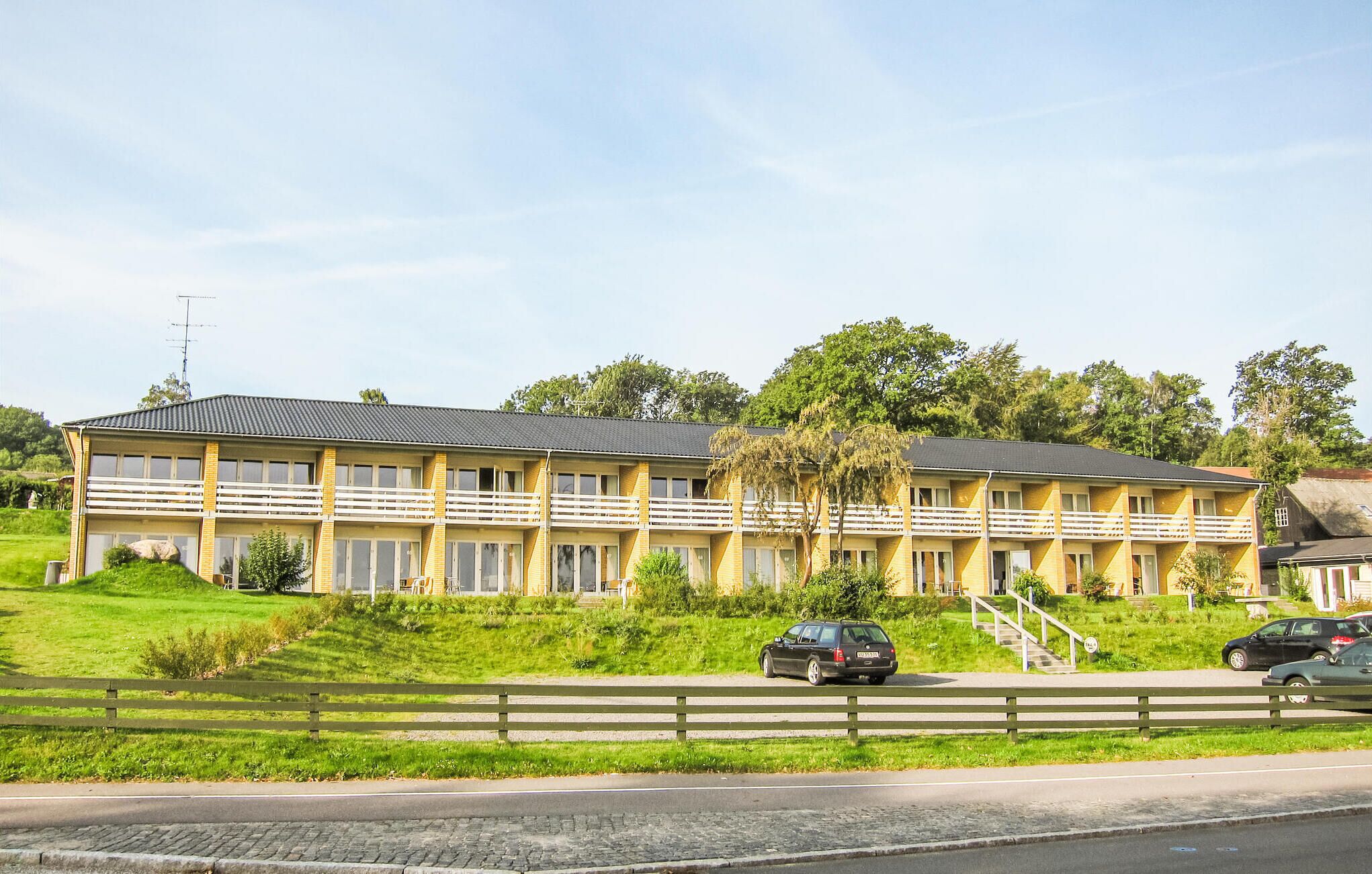 Un motel à deux étages, doté d’un toit plat, de nombreux balcons et d’un parking où sont garées des voitures.